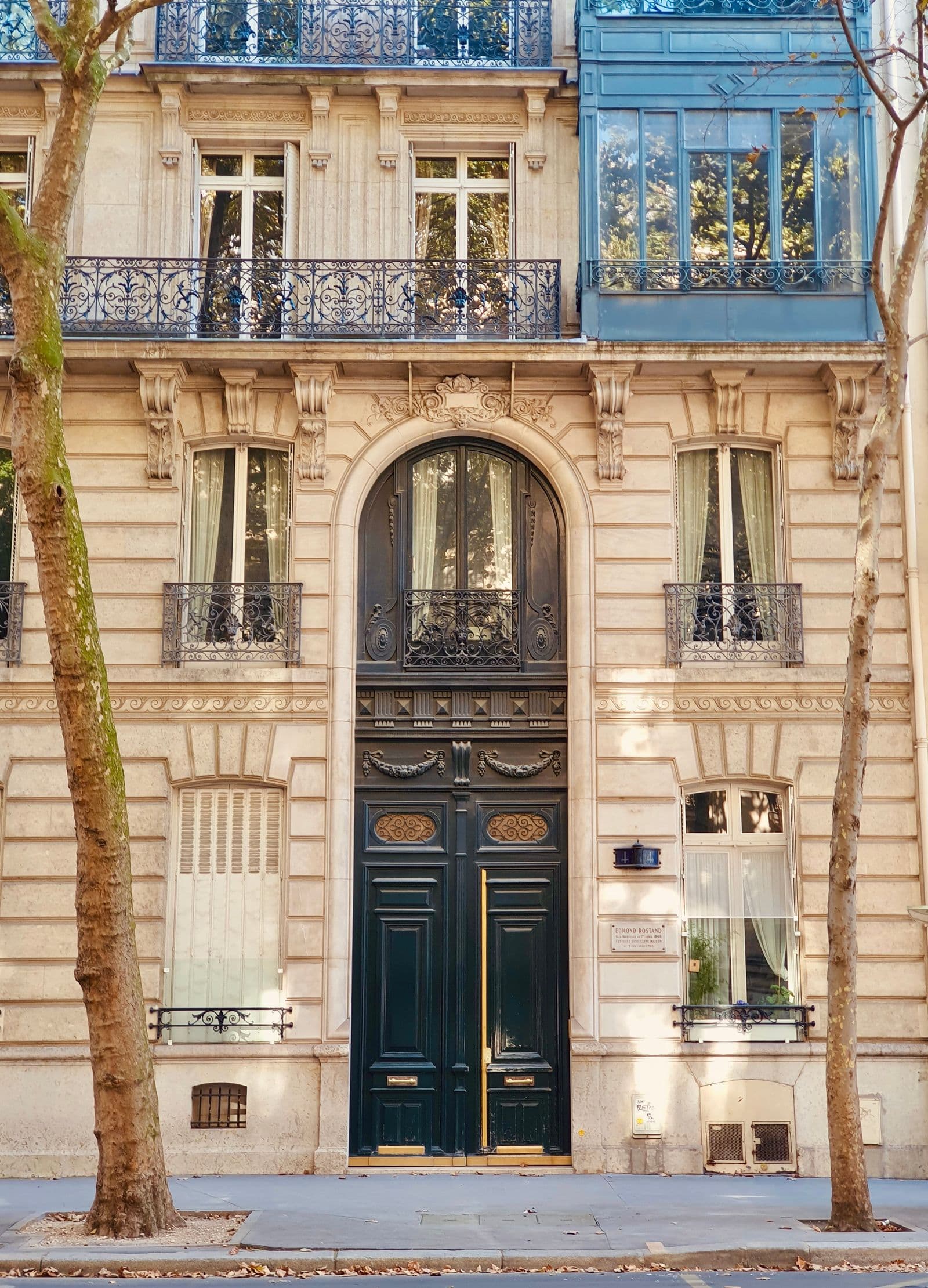Façade haussmannienne en pierre de taille, avec sa porte cochère et ses balcons en fer forgé